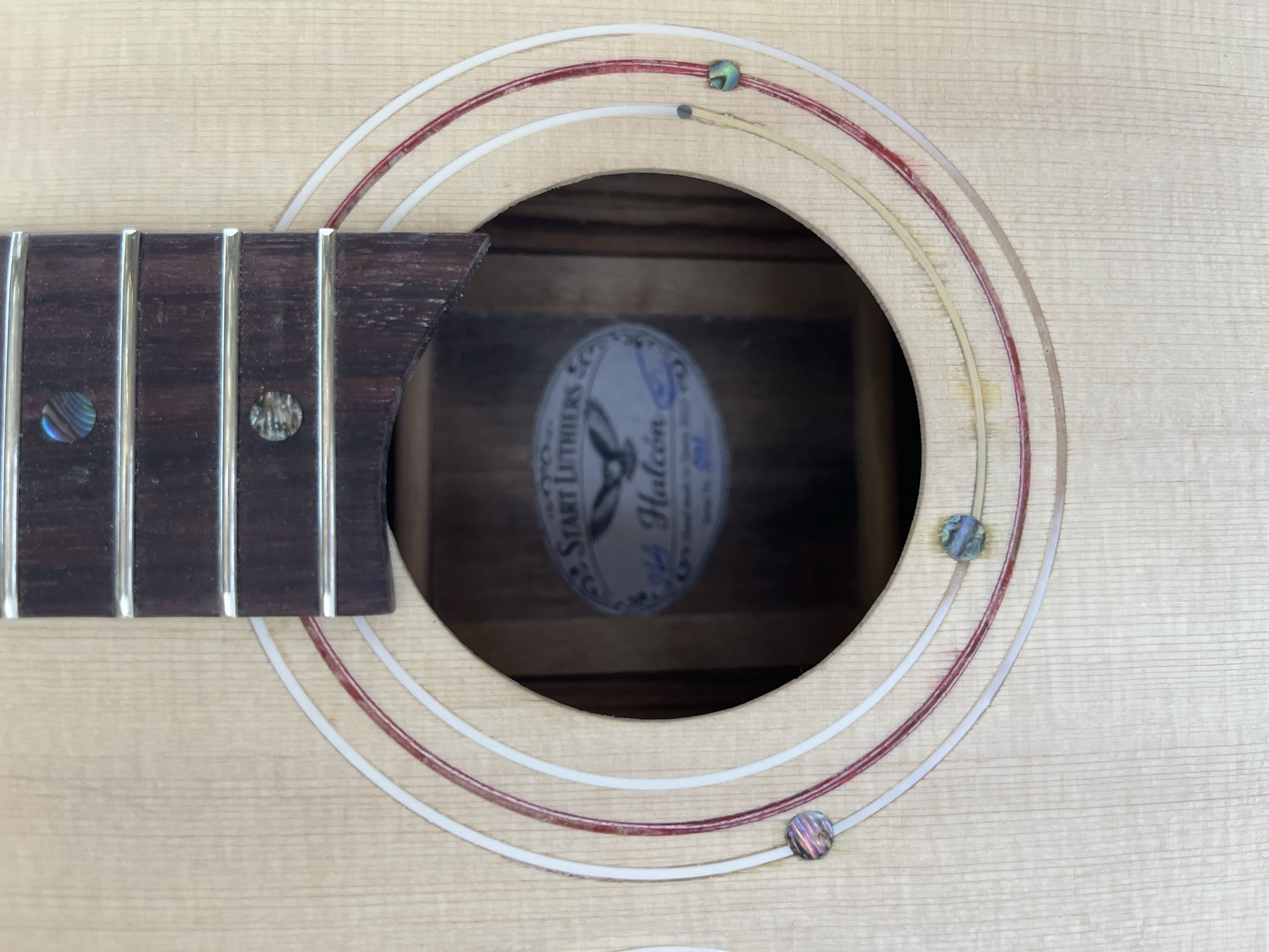 Acoustic guitar soundhole showing the hand-applied Start Luthiers Halcón label