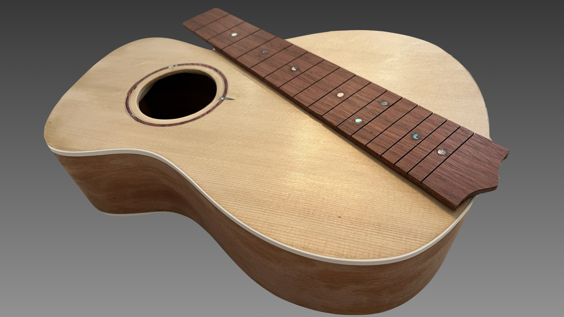 Spruce ukulele top and rosewood fretboard laid out before final assembly